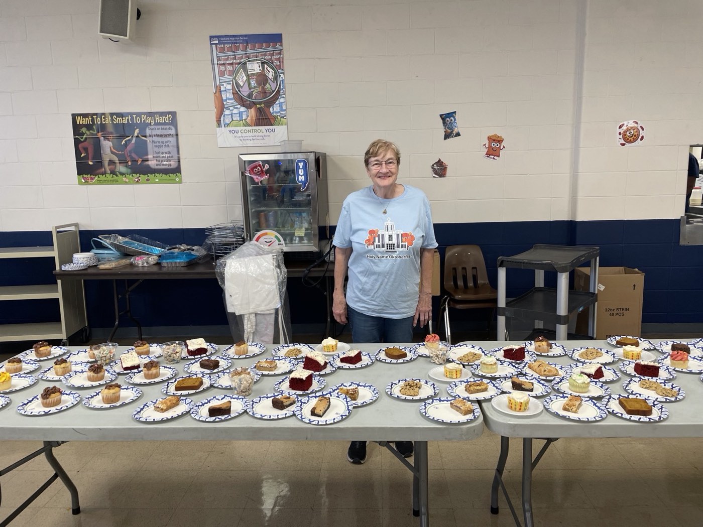 A volunteer standing behind a long table of homemade dessert plates