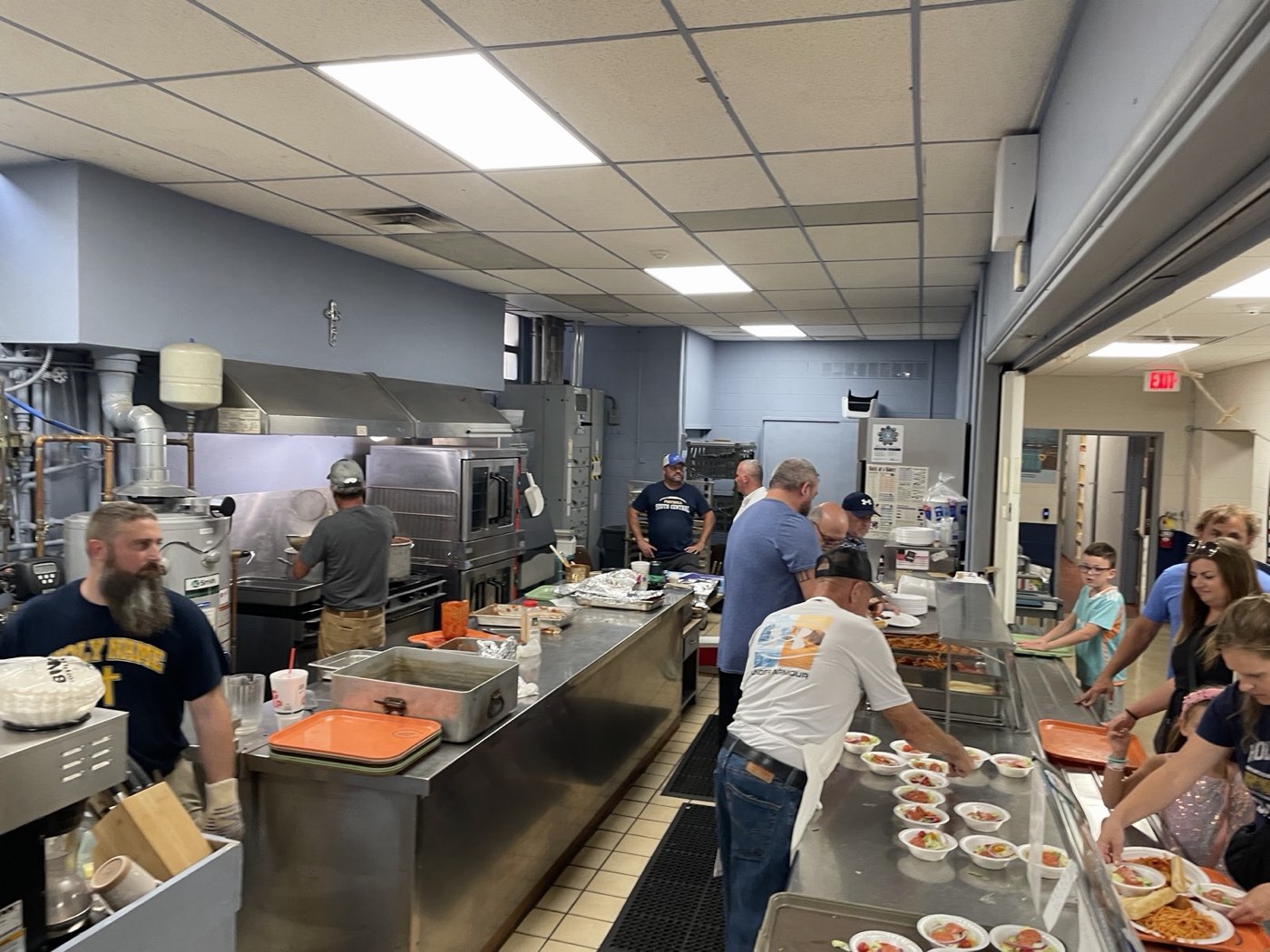 Men's Club volunteers working the kitchen line, plating salads and spaghetti