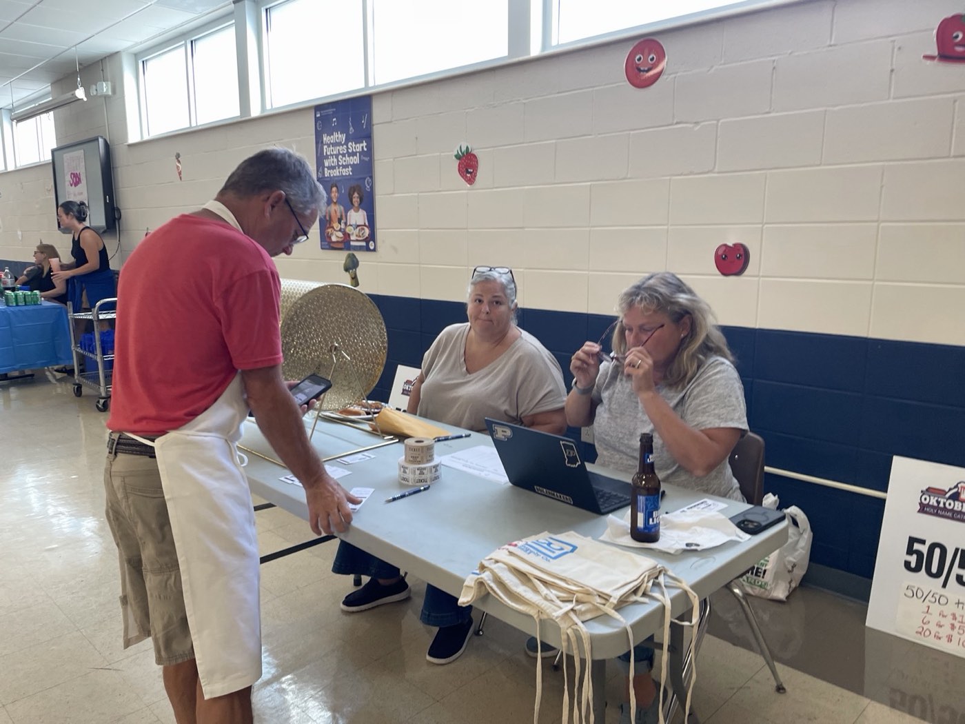 Volunteers selling raffle and 50/50 tickets at a table beside the raffle drum